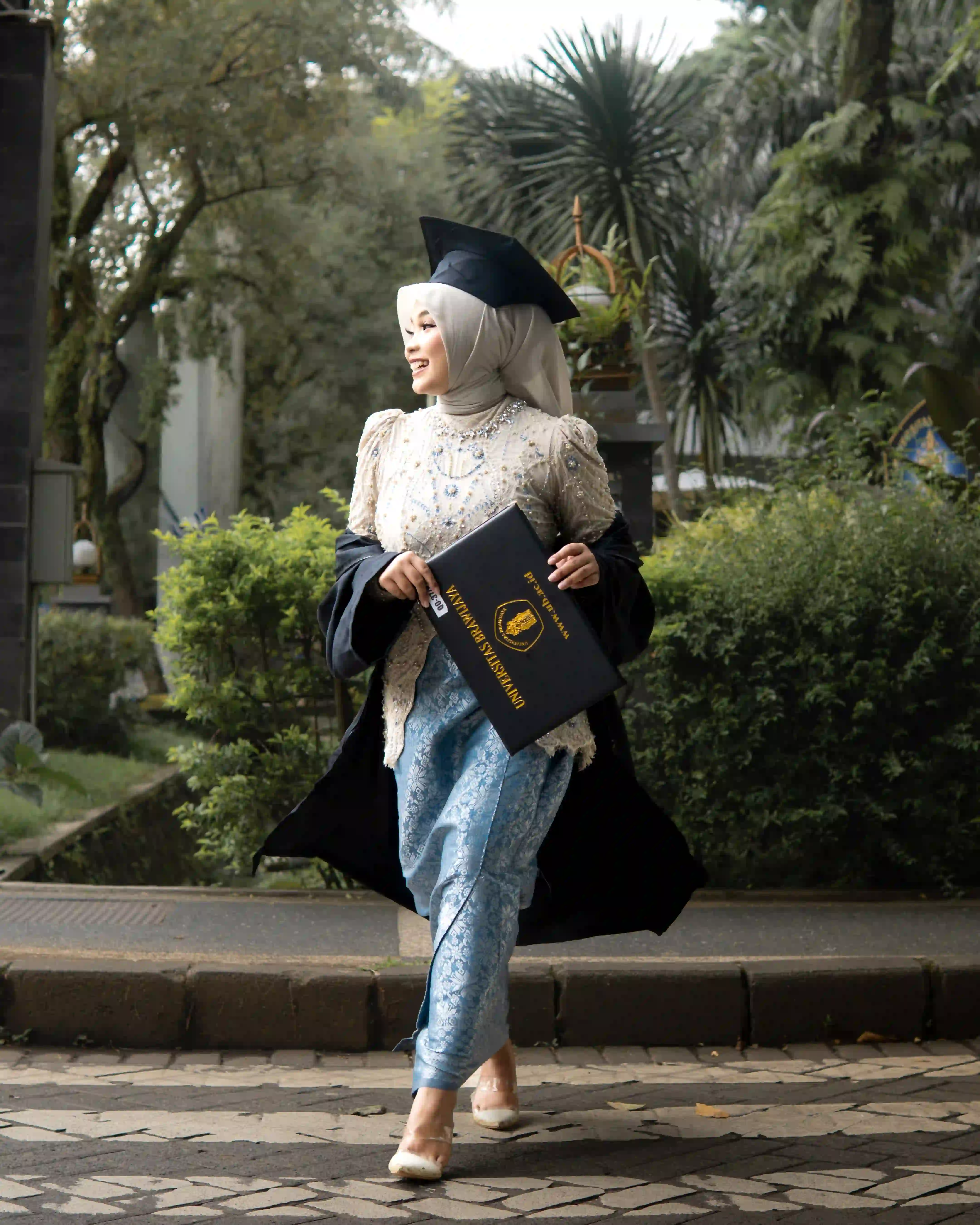 Sesi foto outdoor group wisuda dengan kebaya dan toga berlatar arsitektur ikonik UIN Malang