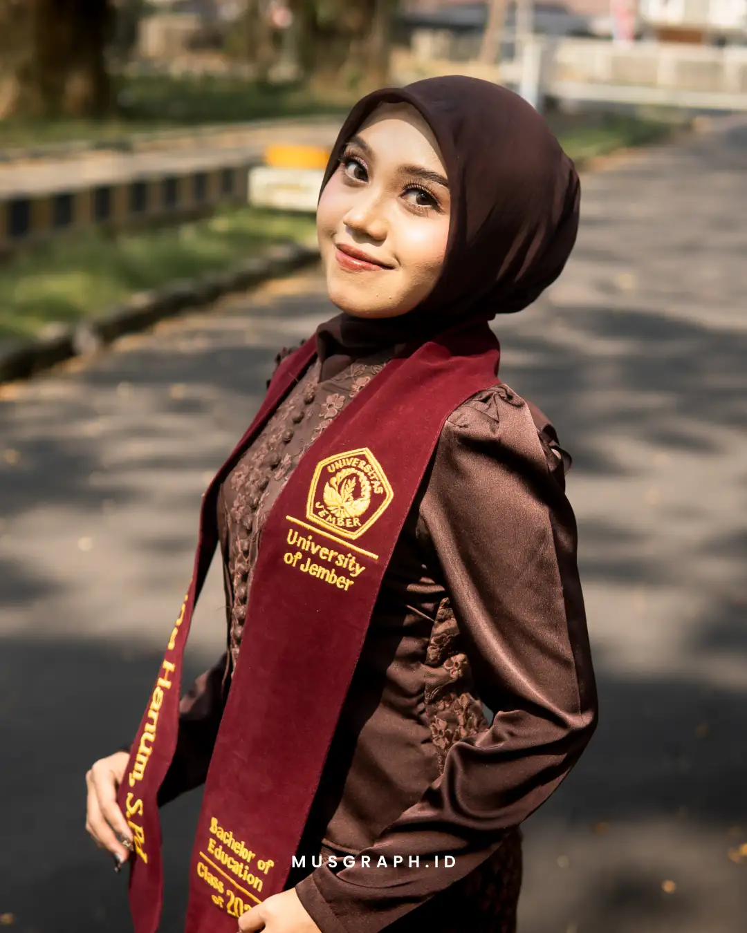 Sesi foto wisuda outdoor di jalur pedestrian kampus UNEJ dengan pencahayaan sore hari